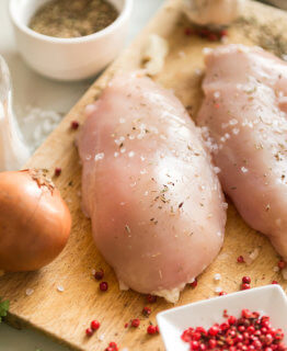 chicken fillet on a cutting Board with spices, chicken meat, salt, onion, pepper, parsley, onion